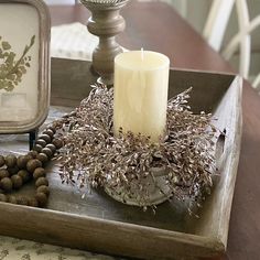 a wooden tray with candles and beads on it, next to a small candle holder