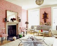 a living room with red and white wallpaper, zebra print rug, fireplace and chairs