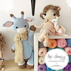 two crocheted stuffed animals sitting next to each other in front of a box of yarn