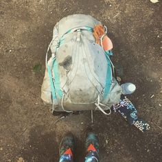 the backpack is sitting on the ground next to someone's feet and shoes,