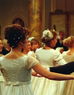 a man and woman dance together in formal dress while other people watch from the back