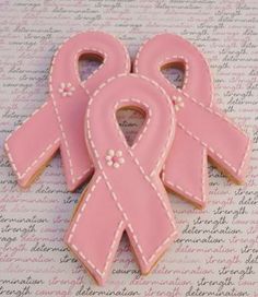 two pink ribbon shaped cookies sitting on top of a table