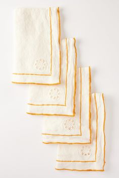 four white and yellow napkins with embroidered designs