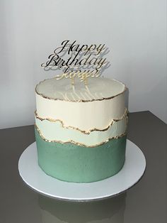 a white and green cake sitting on top of a table with a happy birthday sign