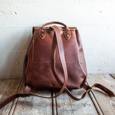 Throw the Emerson Backpack over your shoulder and carry what you need - hands-free, in style. We make this timeless design with Full Grain American Leather, giving it a rustic feel and a classy, vintage look. Not only does it look great, it works great too. The various pockets give this backpack top-notch functionality to match its top-notch style. It features a main compartment with an interior pocket (for quick-access to your keys or phone!), two outer pockets, and a side pocket. Whether you u Bag With Pockets, Leather Hides, Leather Backpack Purse, American Leather, Leather Hide, Personalized Leather, Backpack Purse, Back Strap, Side Pocket