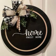 a black and white sign that says home sweet home hanging on a door with a bow