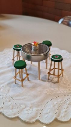 a miniature table and stools on a white doily in front of a bath tub