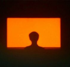 the silhouette of a person in front of an orange square