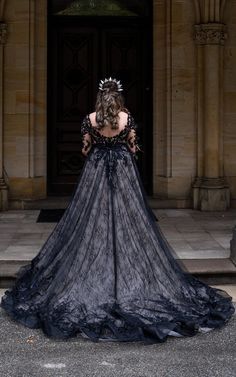 a woman in a long black dress standing on the steps with her back to the camera