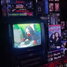 a television sitting on top of a wooden table in front of a bunch of movies