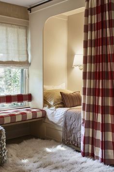 a bedroom with two beds and a red checkered blanket on the floor next to a window