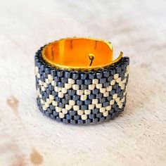 a black and white woven bracelet with an orange center on it's side, sitting on a table