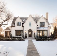 a white house with lots of windows and snow on the ground in front of it