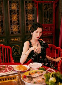 a woman sitting at a table with food in front of her and chopsticks