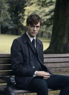 a man sitting on top of a wooden bench