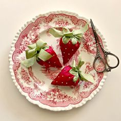 three strawberries are sitting on a plate with scissors