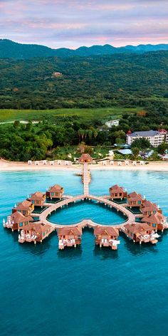 an aerial view of a resort in the middle of the ocean with water and trees around it