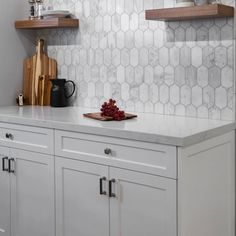 a kitchen with white cabinets and marble backsplash, cutting board on the counter