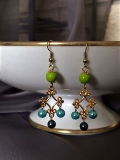 These beautiful pearl and gold chandelier earrings are so fun.  The blue and the green pearls with the gold filigree flowers are such a great combination and really create a classic look.  They catch the light so well and make a chic statement when wearing them.  They go with just about anything.  They look so good on their own but can be paired and layered so easily.  These earrings can be worn for just about any occasion.  They look very glamorous dressed up but also make jeans and a t-shirt l Gold Flower Earrings, Pearl Earrings Gold, Gold Filigree Earrings, Seahawks Fans, Gold Chandelier Earrings, Flower Chandelier, Green Pearls, Filigree Earrings, Gold Chandelier