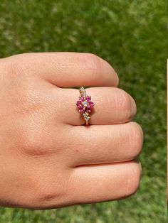 The Amalie Ladies 18K Gold Cocktail Ring set with Rubies and Diamonds. Crafted in desirable 18 karat yellow gold, this ladies ring features 0.20 total carats of rubies in a floral like design accompanying 0.10 total carats of diamonds. The ring is currently a finger size 6.5 and is able to be resized for an additional charge. Each piece has been hand selected and meticulously identified and graded by a Graduate Gemologist who has been awarded a degree by the Gemological Institute of America (GIA Yellow Gold Ruby Cluster Ring For Promise, Yellow Gold Cluster Ruby Promise Ring, Yellow Gold Ruby Cluster Ring With Multi-stone, Gold Cluster Ruby Ring For Promise, Gold Cluster Ruby Promise Ring, Gold Ruby Cluster Ring, Cluster Yellow Gold Ruby Ring In Fine Jewelry Style, Yellow Gold Cluster Ruby Ring, Gold Ruby Ring With Rose Cut Diamonds Cluster