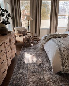 a bedroom with a bed, dresser and chair in front of a large open window