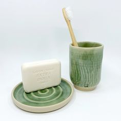 a toothbrush and soap on a plate next to a cup