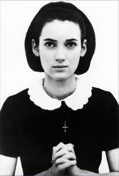 black and white photograph of a woman with a cross on her neck holding hands together