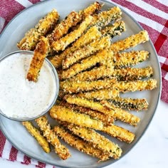 fried asparagus on a plate with ranch dip in the middle and garnished with parmesan cheese