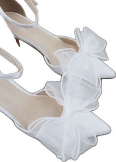 a pair of white shoes with bows on them