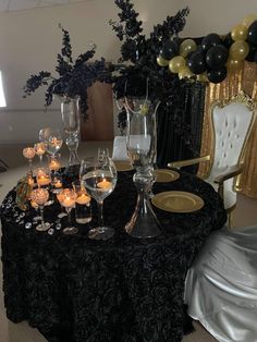 a table topped with lots of wine glasses and candles next to a vase filled with flowers