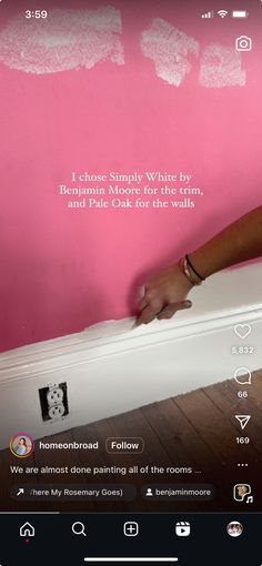 someone is painting the wall with pink and white paint in their home, using her phone