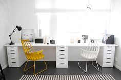 a white desk with two yellow chairs and a black and white rug in front of it