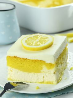 a slice of lemon cake sitting on top of a white plate with a fork next to it