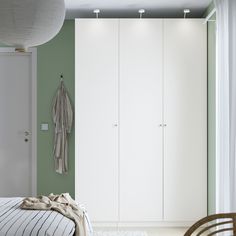 a bedroom with green walls and white closets in the corner, next to a bed