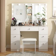 a white vanity with lights on it next to a bed and dresser in a bedroom