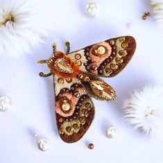 a close up of a moth on a white surface with flowers in the background and pearls scattered around it