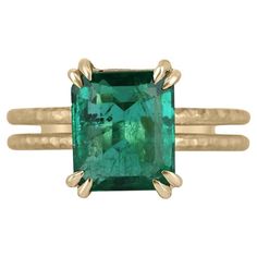 This exquisite solitaire ring features a natural 3.43-carat emerald cut emerald that boasts a stunning, vivid dark green color with excellent-very good luster that captivates the beholder. The emerald is set in a double claw prong basket, which is beautifully crafted from 14k yellow gold with a matte hammered finish. The split shank design adds a touch of modernity to this classic piece, making it a true standout. A breathtaking choice for a proposal, anniversary, or special occasion, this ring Emerald Ring Vintage, Emerald Ring Gold, Split Shank Ring, Dark Green Color, Solitaire Setting, Claw Prong, Zambian Emerald, Yellow Gold Setting, Split Shank