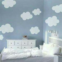 a bedroom with blue walls and white clouds painted on the wall