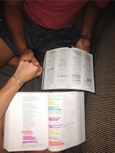 two people sitting on a couch holding hands over an open book with colored lines in it