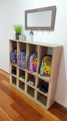 a wooden shelf filled with school supplies on top of a hard wood floor next to a mirror