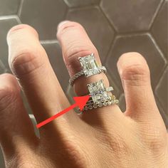 a woman's hand with two engagement rings on it and an arrow pointing to the ring