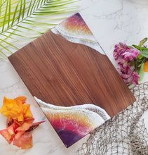 a wooden cutting board sitting on top of a table next to flowers and other items