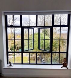 an open window with a teddy bear sitting in the window sill next to it