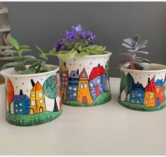 three potted plants with houses painted on them