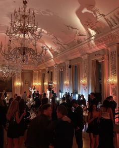 a group of people standing in a room with chandeliers