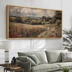 a painting hanging on the wall above a couch in a room with a table and lamp