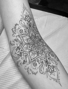 a woman's leg with a tattoo on it that has an intricate design in black and white