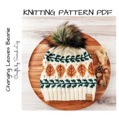 a knitted hat with a pom - pom sits on top of a wooden plate