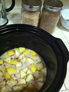 a crock pot filled with potatoes and seasoning next to two salt shakers