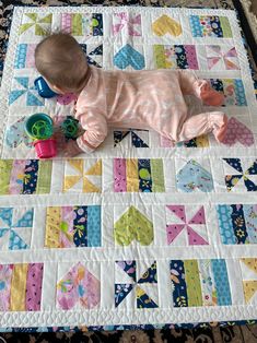 a baby laying on top of a colorful quilt